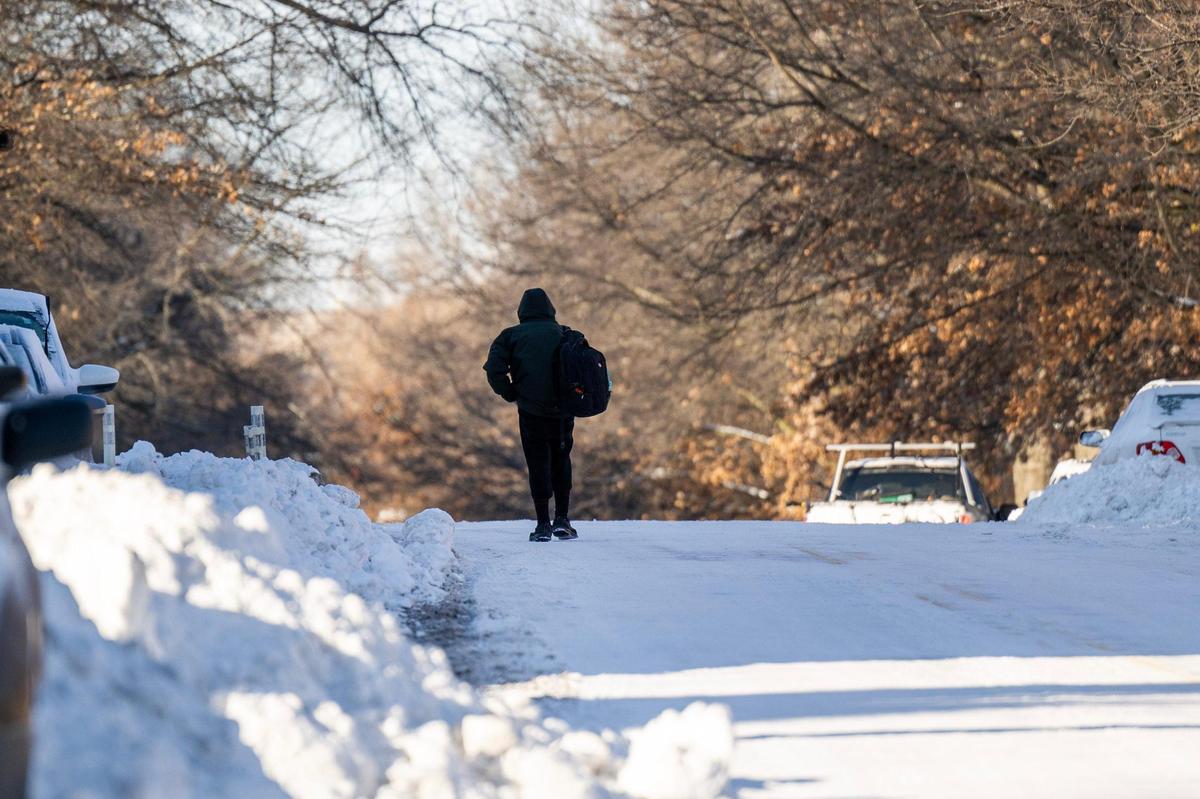 A person walks along Armour Boulevard, navigating the street due to unplowed sidewalks, as snow blankets the neighborhood on Monday, Jan. 6, 2025, in Kansas City.