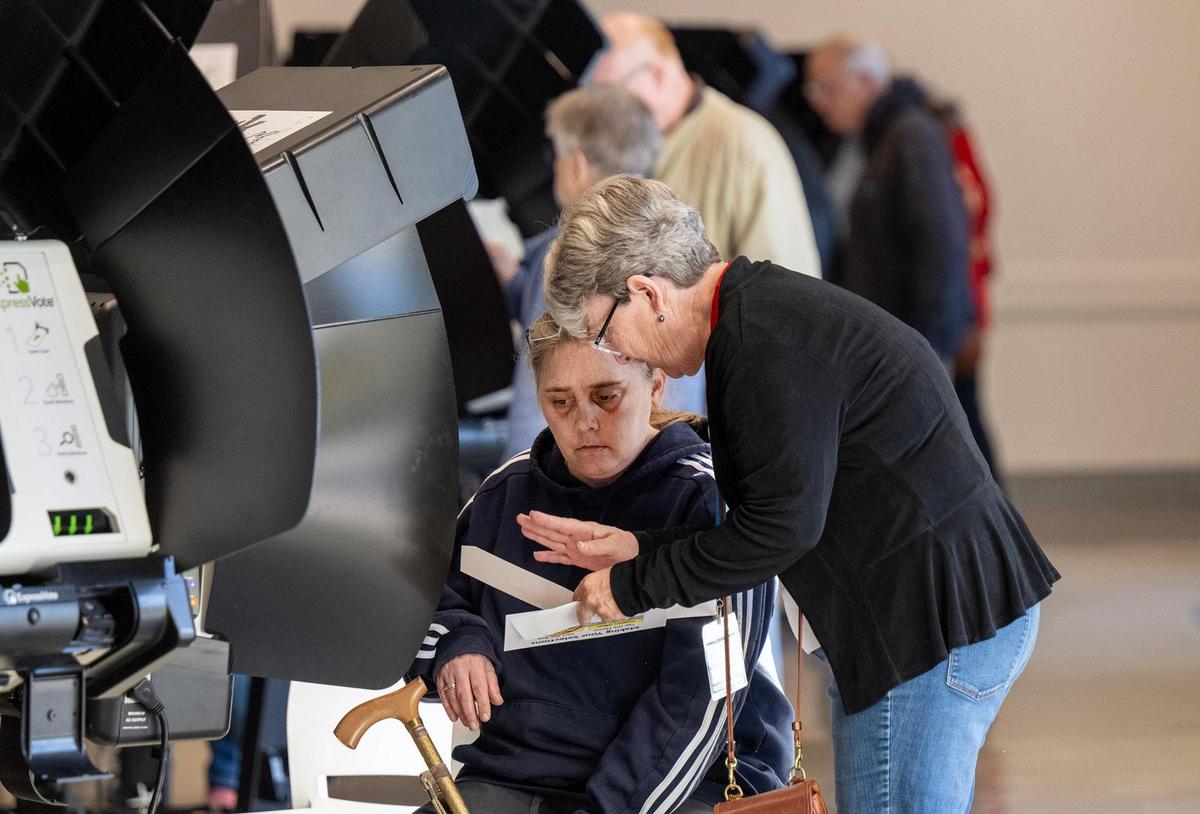 An election worker, right, assisted a Johnson County resident during the first day of in-person advance voting for the 2024 General Election at The Arts and Heritage Center on Saturday, October 19, 2024, in Overland Park.