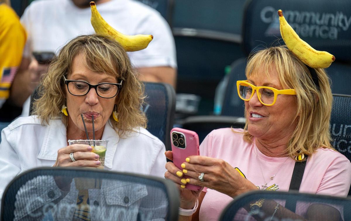 Terri Engroff, left, and her twin sister Toni Marengo wear banana-themed attire as they attend a Banana Ball game against the Firefighters at Kauffman Stadium on Friday, May 23, 2025, in Kansas City.