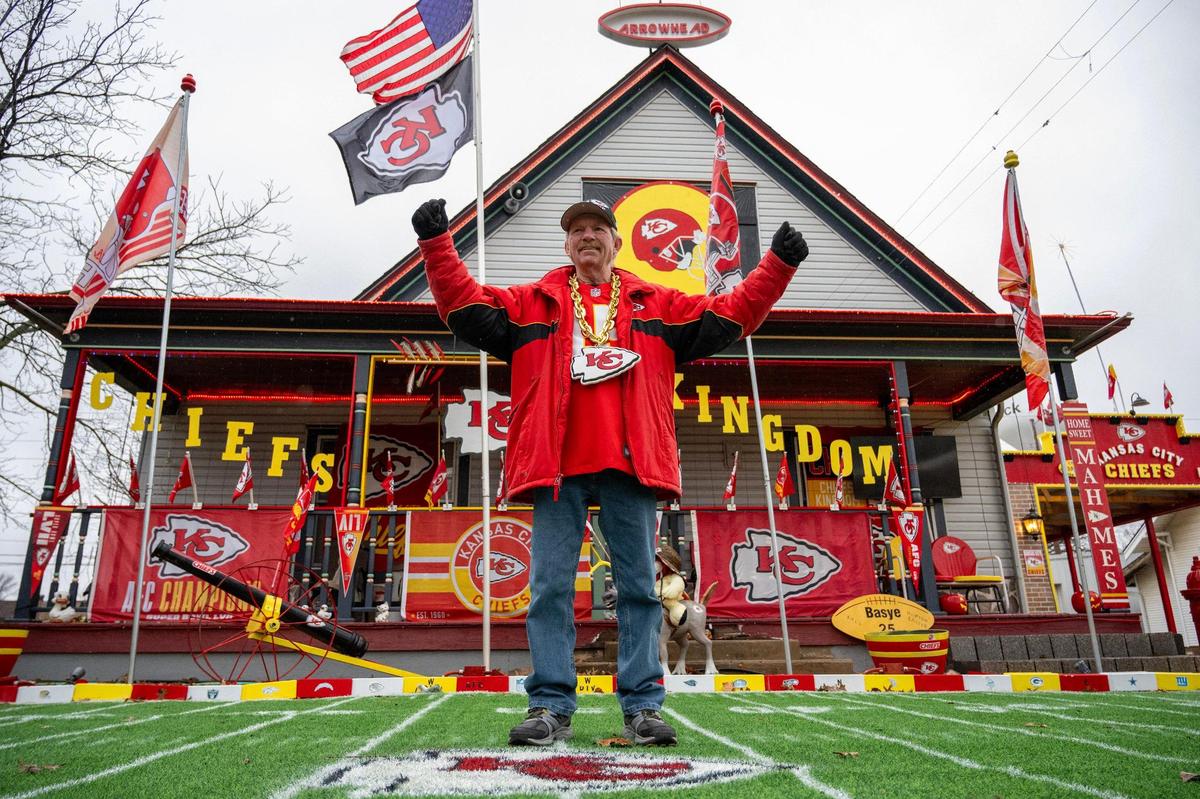 Dennis Basye, a dedicated Kansas City Chiefs super fan, raises his arms in front of his home on Sunday, Feb. 4, 2024, in Sedgwick, Kansas. Basye, who has been collecting Chiefs merchandise for five years, annually enhances his house display with new additions.