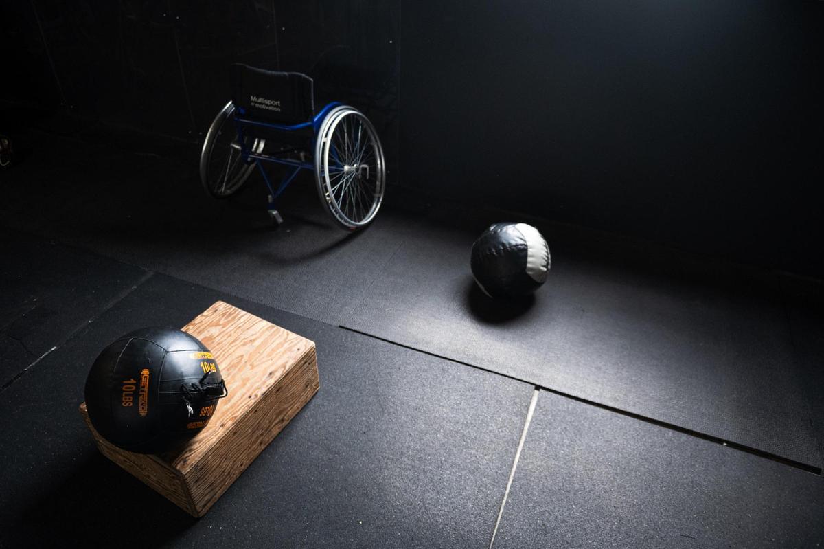 Medicine balls sit on the floor near an unused wheelchair after an Adaptive Athletes in Motion workout at Brave Enough CrossFit.