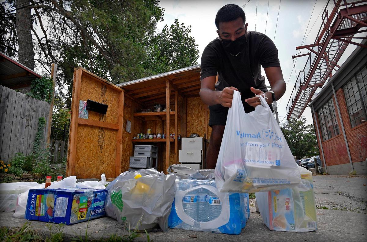 Sayan Grover, a student at the University of Kansas, stocks a food pantry located behind Latchkey Deli, a restaurant on Massachusetts Street in Lawrence.