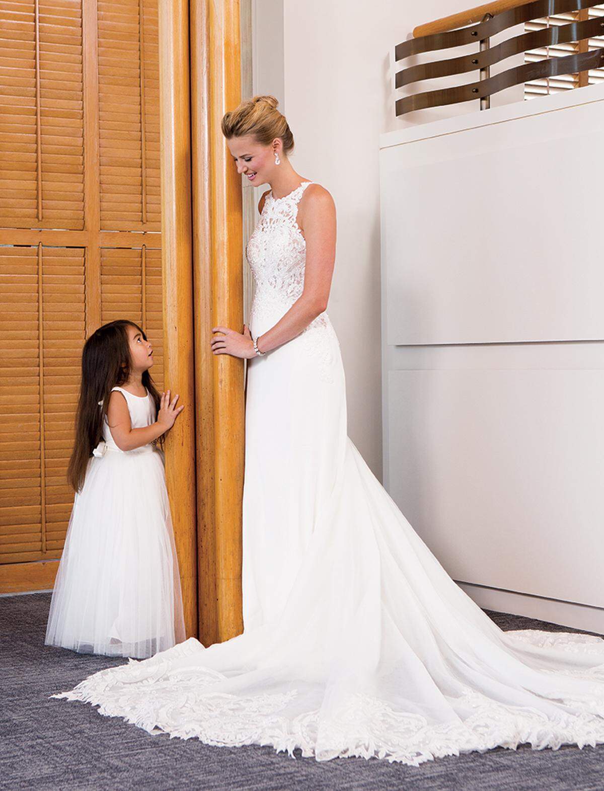SWEET AND SIMPLE On bride: Martina Liana dress with high neckline and ivory-beaded bodice, $3,599, round Bling earrings, $90, and bracelet, $85, from Belle Vogue Bridal. On flower girl: Rosebud satin flower-girl dress with beaded belt, $158, from Bella Bridesmaids. Lace Stuart Weitzman “Fannie” ballet flats, $52, from Kid Oh! in Halls Kansas City.