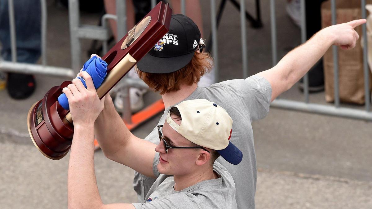 Mitch Lightfoot lifts the trophy as he rides in the parade with Chris Teahan. Thousands of fans gathered along Massachusetts Street in downtown Lawrence Sunday, April 10, 2022, to celebrate the Kansas Jayhawks men’s basketball team, the 2022 NCAA champions.