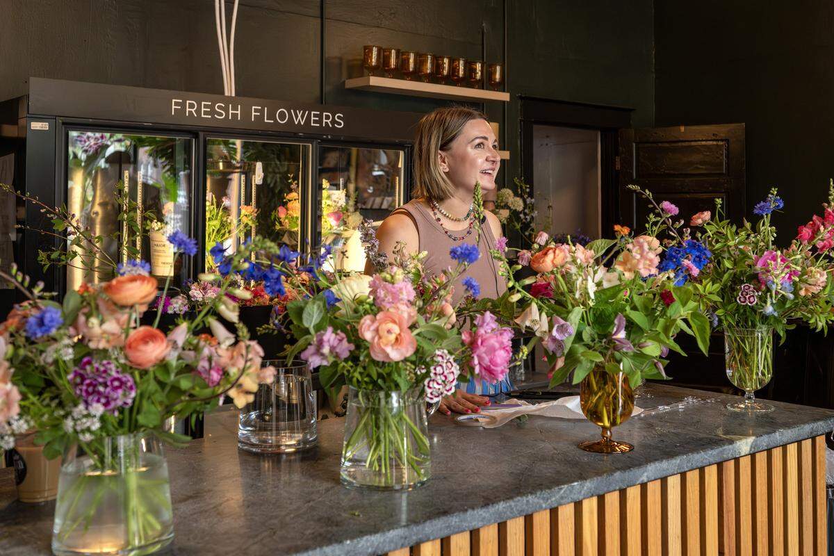Betsy Ford, co-owner of Lily Floral Collective, arranges flowers into glass vases on Friday, May 8, 2026, in Kansas City.