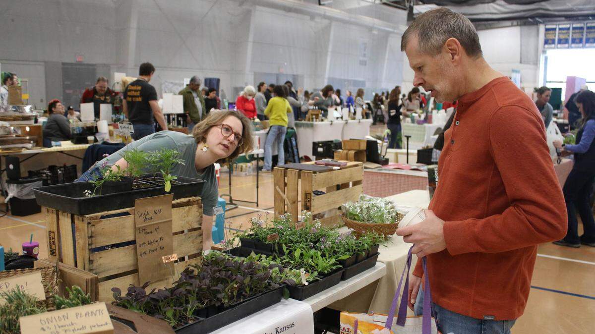 Kristin Selby, program manager for New Roots for Refugees, chats with Brett Logwood of Olathe at the Eat Local & Organic Expo at Johnson County Community College.
