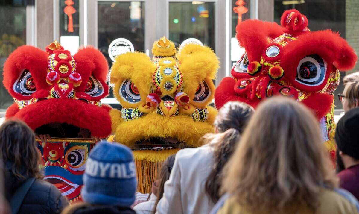 People gather around the Th?n Phúc Lion Dance team for photos after a performance during a Lunar New Year celebration at the Lenexa Public Market on Sunday, Feb. 22, 2026, in Lenexa.