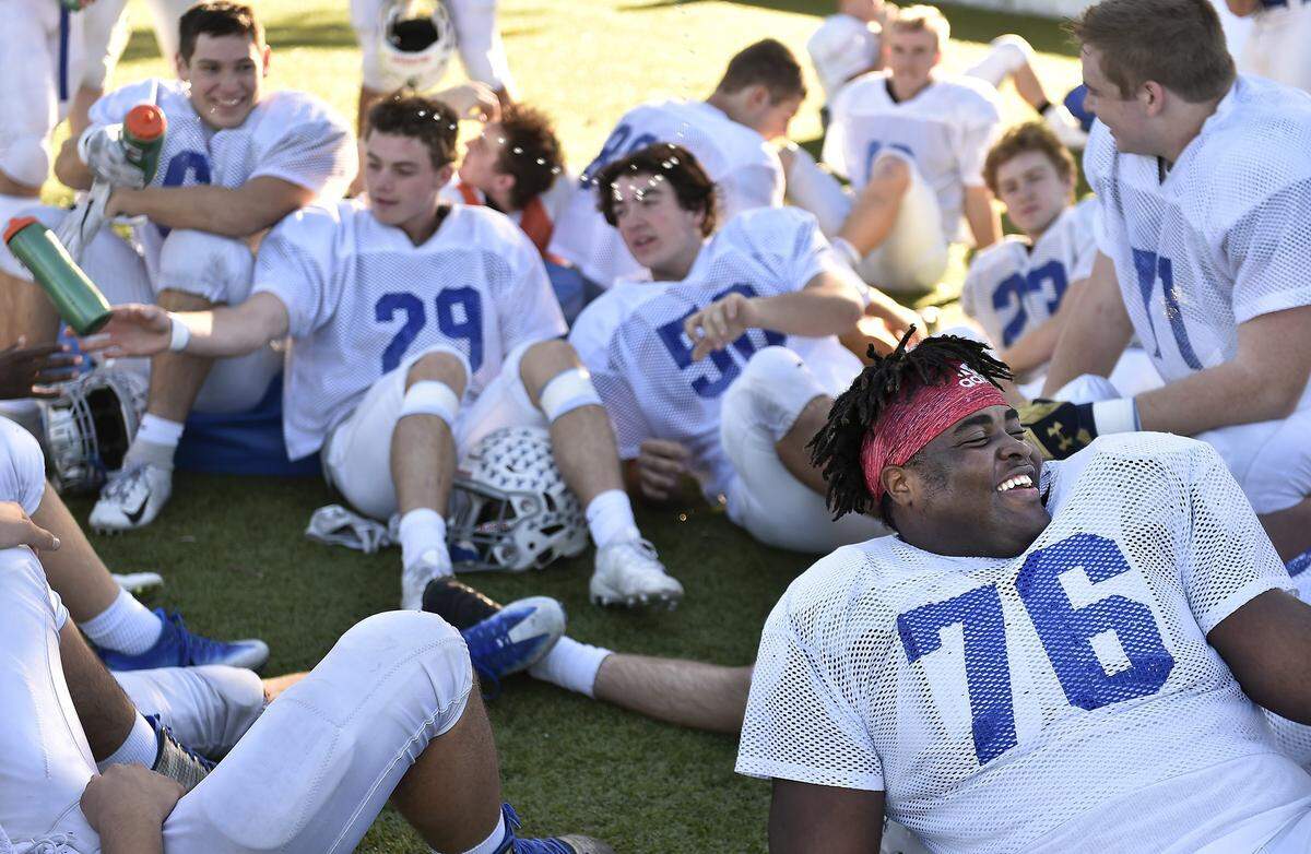 A Rockhurst High teammate plays around by spraying water on Danielson Ike (bottom right) during a break in practice.