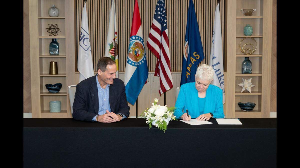 BJC HealthCare President and CEO Richard Liekweg watches Saint Luke’s CEO Melinda Estes sign the agreement to merge the two healthcare systems. The merger becomes official on Jan. 1.