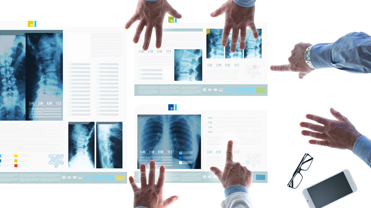 Professional medical team examining patient’s medical records and x-ray on touch screen slides and pointing