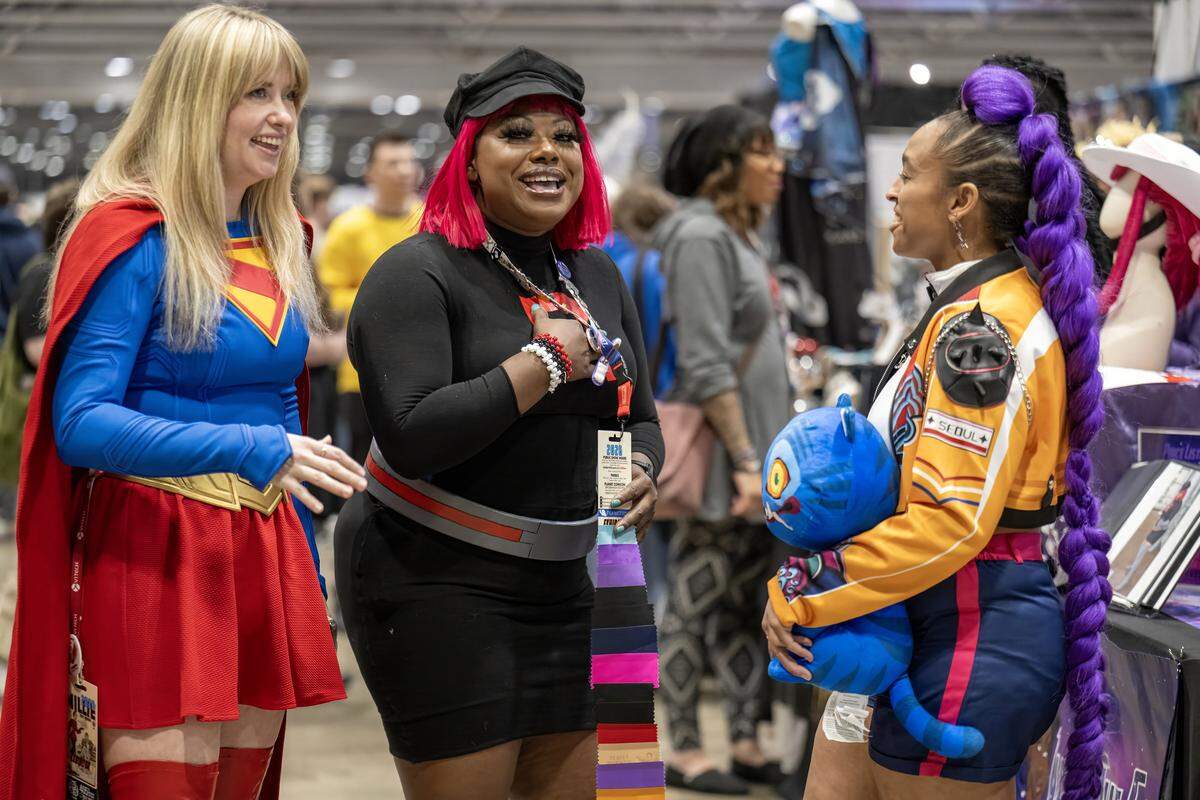 Cosplayers Caroline Nelson of Just-us League in her Supergirl attire and Heather Geran as Rumi of the Kpop Demon Hunters visited with Diana Alexander, center, known to fans as "Diana the Great,"  during festivities Sunday, March 29, 2026, at Planet Comicon Kansas City. Alexander is know for her cosplay and making costumes. 