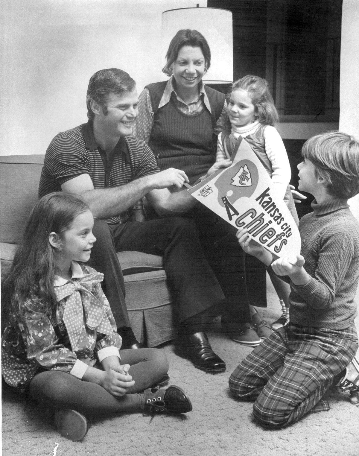 Joseph D. McManara, 38-year-old New York police officer who became Kansas City Chief of Police in 1973, and his family contemplate becoming Kansas City Chiefs fans with a pennant McNamara took home in suburban Valley Cottage, N.Y. Left to right with McNamara are Laura McNamara, 7, Mrs. Rochelle McNamara, Karer McNamara, 5, and Donald McNamara, 8.