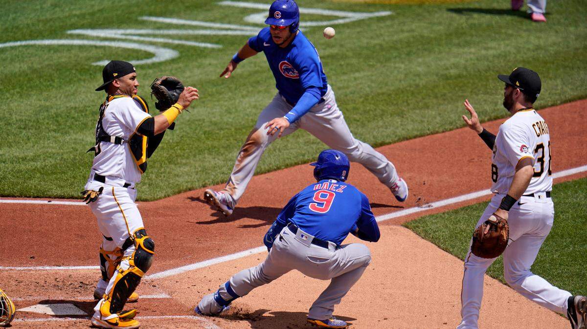 Pittsburgh Pirates first baseman Will Craig, right, tosses the ball to catcher Michael Perez, left, after Chicago Cubs’ Javier Baez (9) hit a fielder’s choice third to first and was caught in a rundown between home and first during the third inning of a baseball game in Pittsburgh, Thursday, May 27, 2021. Cub’s Willson Contreras, top center, scores on the play and Báez reached second on an errant throw by Pirates’ catcher Perez. (AP Photo/Gene J. Puskar)