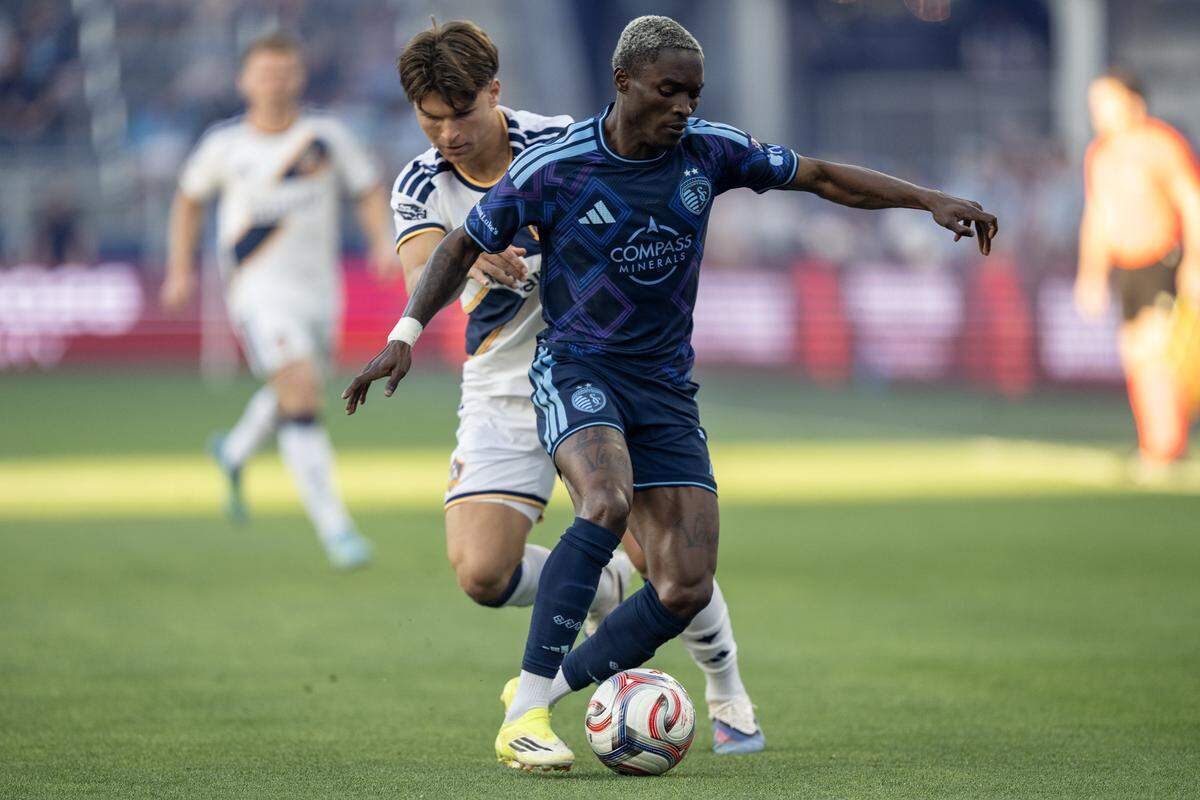 Sporting Kansas City forward Capita Capemba, right, dribbles past L.A. Galaxy forward Rubén Ramos Jr. during the first half of a Major League Soccer match at Sporting Park in Kansas City, Kansas on Wednesday, May 13, 2026.