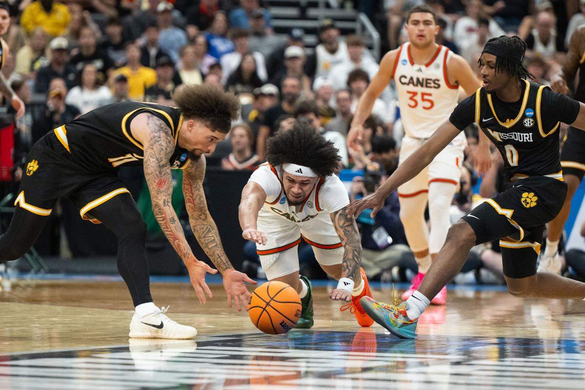 Miami Hurricanes guard Tre Donaldson (3) dives for the ball between two Missouri Tigers players in the Tigers first-round NCAA Tournament matchup vs. the Miami Hurricanes at Enterprise Center in St. Louis on Friday, March 20, 2026.