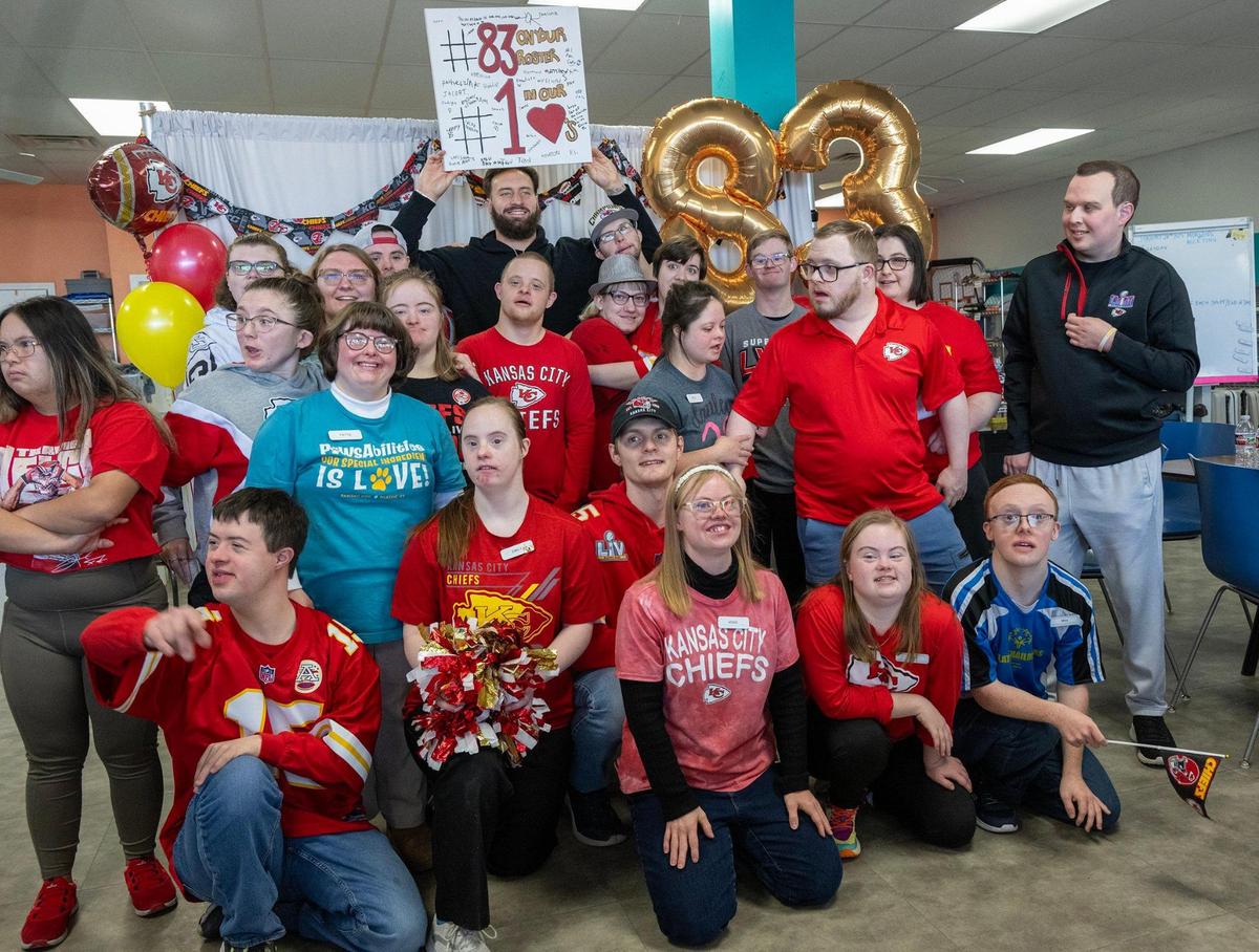 Chiefs tight end Noah Gray holds up a hand-painted sign given to him by the students at PawsAbilities during a visit to the non-profit on Wednesday in Olathe.