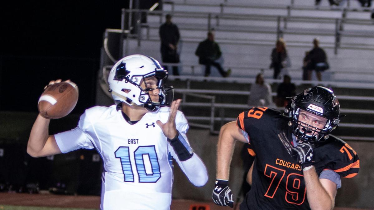 Shawnee Mission East quarterback Andy Maddox got off pass while trying to keep away from SM Northwest’s Dylan Bruner in action on Friday night.