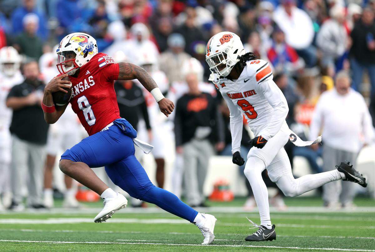 Kansas Jayhawks quarterback Jalon Daniels, left, takes off for a gain during a college football game against the Oklahoma State Cowboys at David Booth Kansas Memorial Stadium in Lawrence, Kansas, on November 1, 2025.