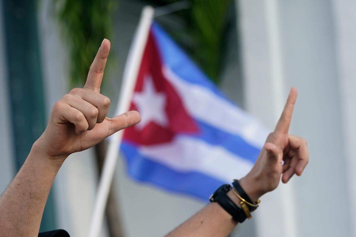 Demonstrators sign the letter “L,” for liberty and wave flags, Wednesday, July 14, 2021, in Miami’s Little Havana neighborhood, as people rallied in support of anti-government demonstrations in Cuba.
