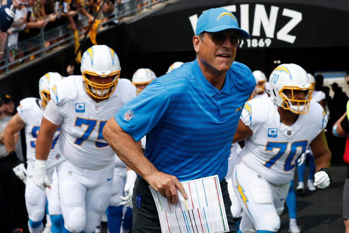 Los Angeles Chargers head coach Jim Harbaugh leads his team onto the field to play the Pittsburgh Steelers at Acrisure Stadium.