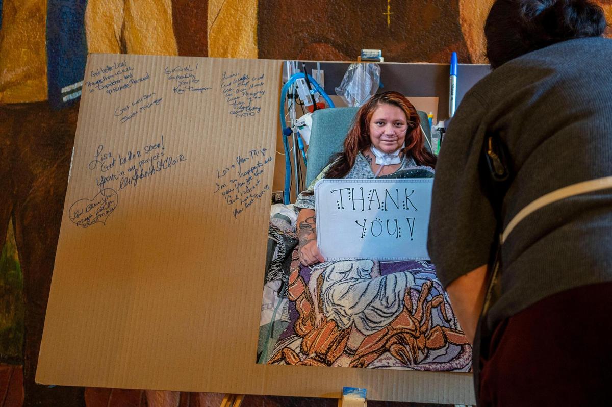 People sign a poster board during a March 19 fundraiser for Lisa Sidenstick at Guadalupe Centers in Kansas City. Sidenstick was in a medically-induced coma for weeks with a severe case of COVID-19.