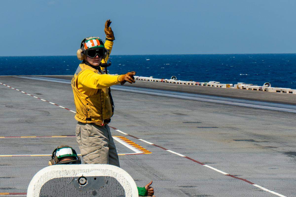 Aboard the USS Harry S. Truman, a plane director prepares to start the catapult process that can launch an aircraft from zero to 165 mph in two seconds.