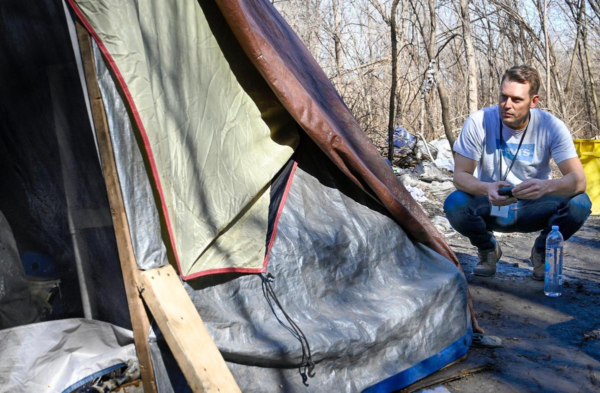 Josh Henges, Houseless Prevention Coordinator for Kansas City, talks to a man living in the tent in a wooded area not far from Independence Avenue on Wednesday, March 2, 2022, in Kansas City. Henges was conducting Point-in-Time (PIT), a count of sheltered and unsheltered people experiencing houselessness.