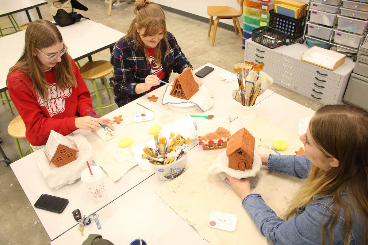 Kira McDaniel of Shawnee and Madilyn Mills of Prairie Village paint their ceramic gingerbread houses with help from teacher Amanda Clark at the Johnson County Arts and Heritage Center.