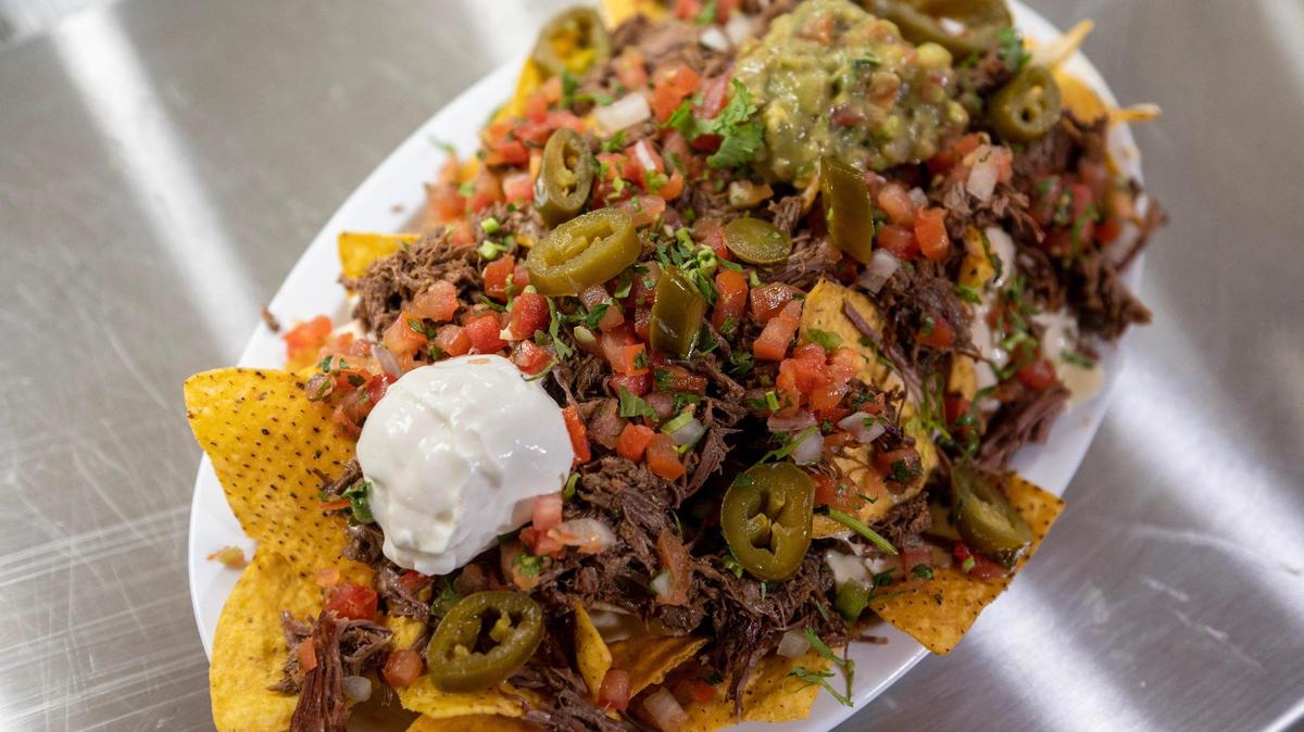 A platter of nachos at Taqueria La Nueva comes with sour cream, guacamole, pico de gallo, jalapeños and shredded beef.