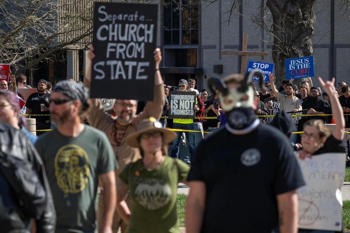 Attendees participate in the Satanic Grotto’s Black Mass ritual as counter-demonstrators stand behind yellow caution tape at the Kansas State Capitol on Friday, March 28, 2025, in Topeka.