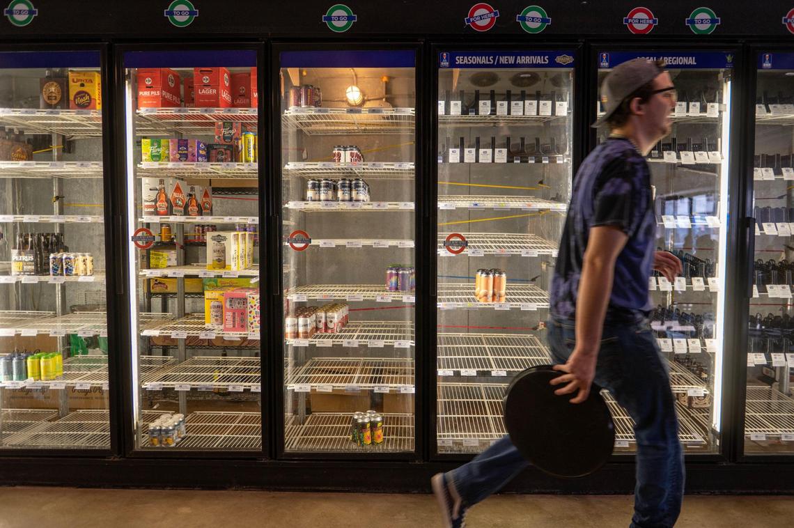 Server Dorian Burton walks by empty coolers at Bier Station on Saturday.