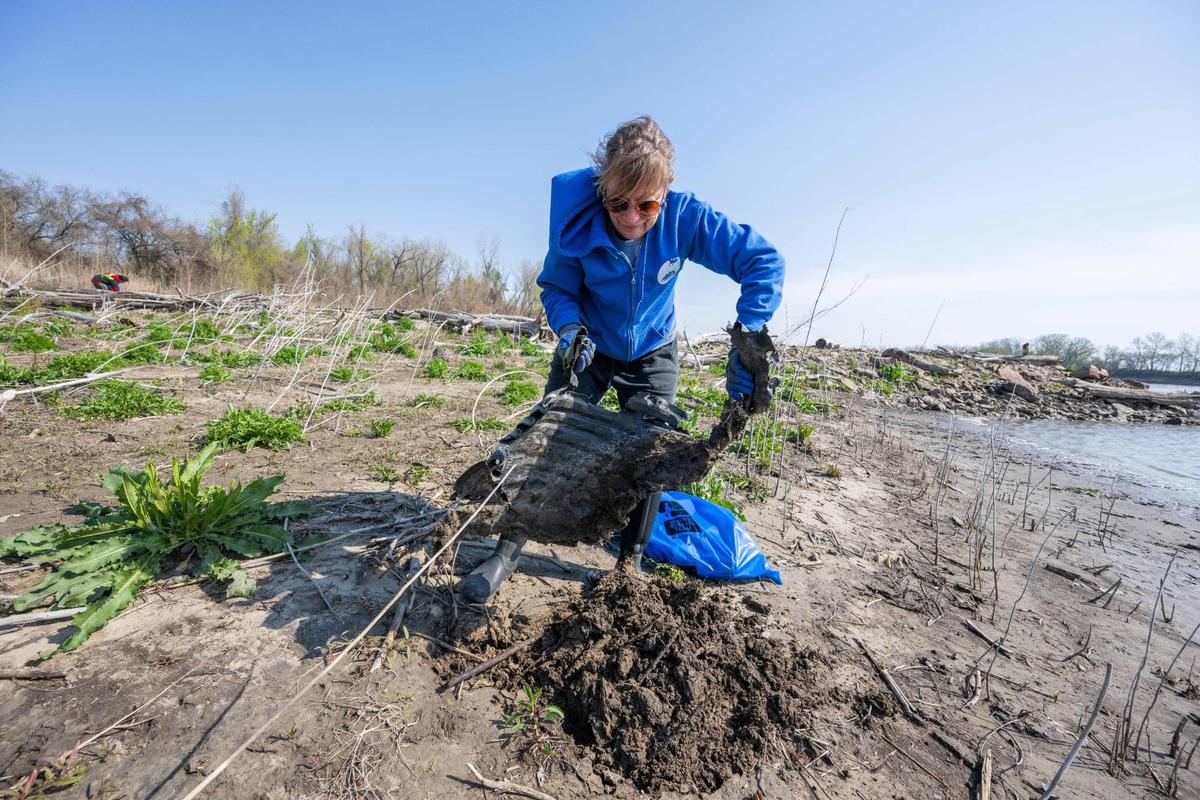 Lisa LaCombe pulls a large piece of plastic from the banks of the Missouri River during Saturday’s cleanup event.