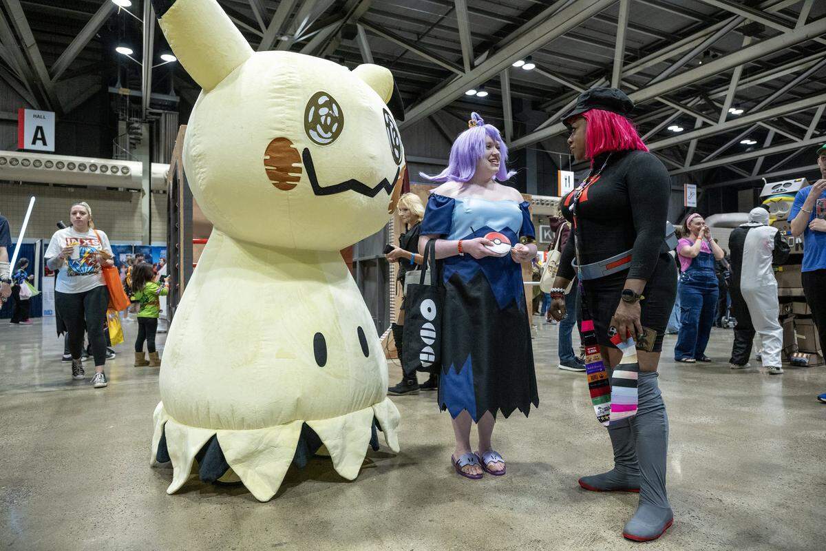 Legacy Reser of Topeka, dressed as the Ghost-type trainer Acerola from Pokémon, speaks with cosplayer Diana Alexander at Planet Comicon Kansas City on Sunday, March 29, 2026. A Mimikyu, Acerola's signature companion, was on hand as part of the ensemble at the Bartle Hall festivities.