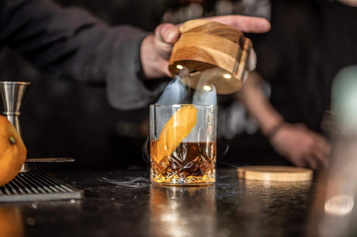 Greg Perrin lifts the cover from an Old Fashioned, allowing smoke to escape, at Audrey's Wine + Bourbon on Thursday, Feb. 5, 2026, in the Waldo neighborhood of Kansas City.