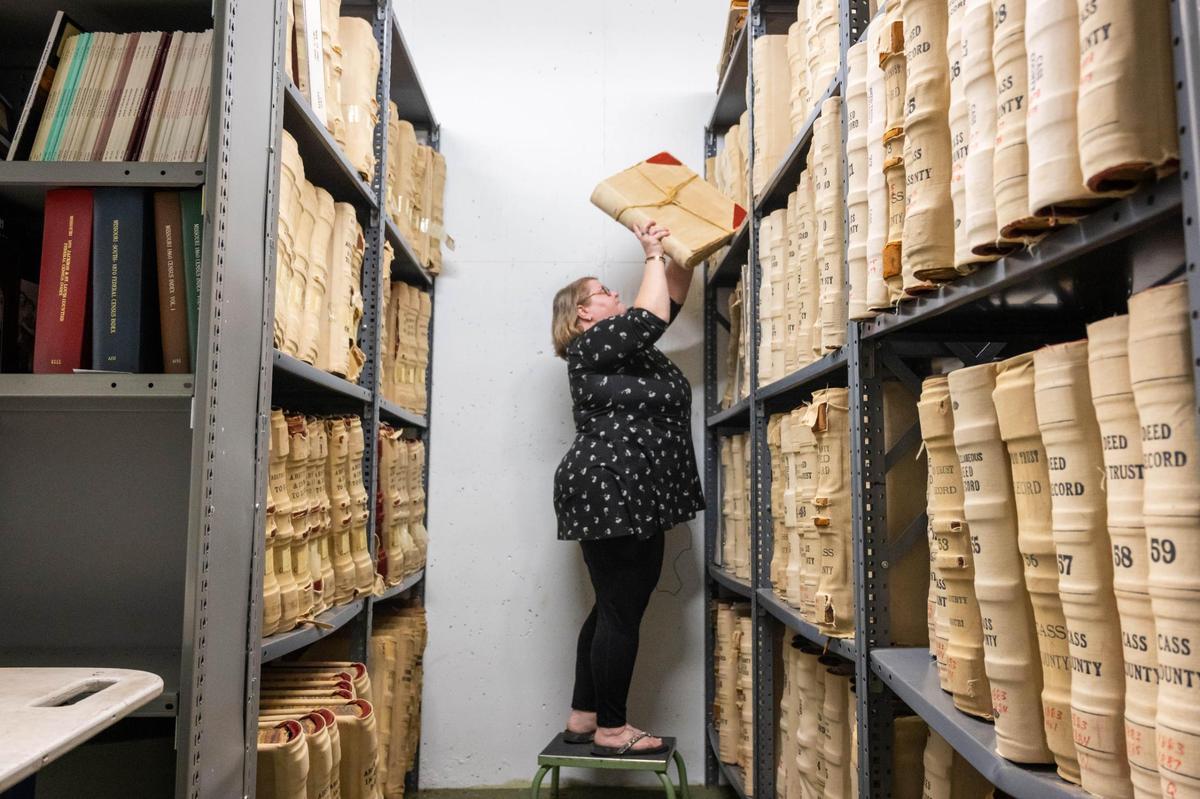 Cass County Historical Society director Jennifer Reed pulls down a large record book while combing through the archives located at the Cass County Public Library Harrisonville Branch on Thursday, Mar. 20, 2025.