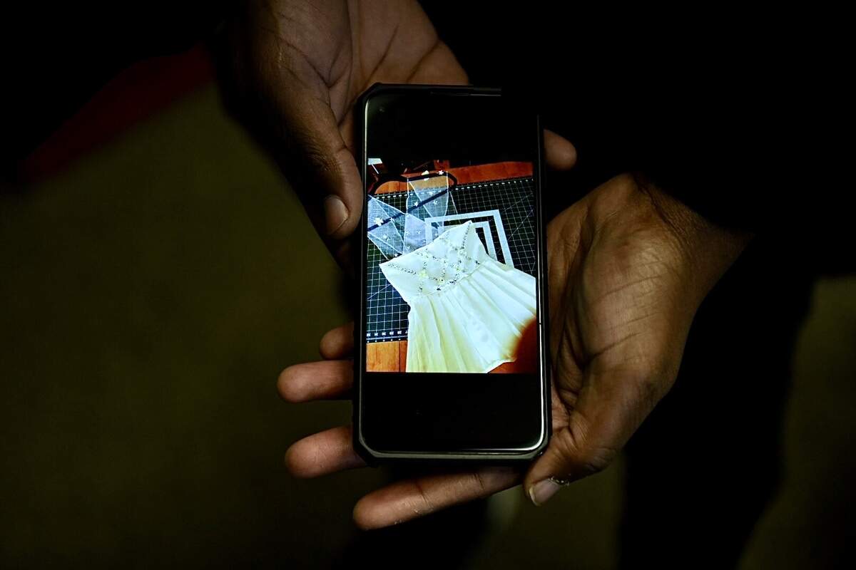 Alex, 25, a survivor of domestic violence and abuse, shows a photo of a dress they are sewing as part of a job training program through the Newhouse Domestic Violence Shelter in Kansas City. The shelter is hurting for money and resources as a result of the pandemic.