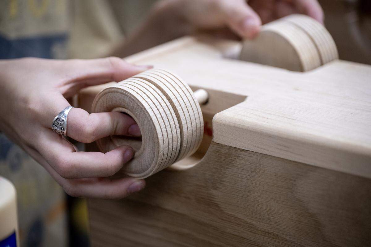 Wheels are secured in place by a volunteer working with Jay Morris of JHM Woodworks to transform donated wood scraps into toy trucks on Tuesday, Dec. 2, 2025 in Lawrence, Kansas. Morris will donate 115 handmade trucks to the Toys for Tots program.