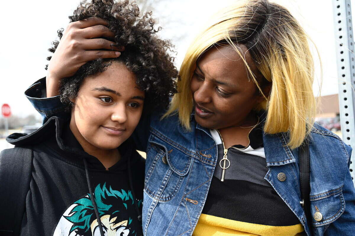 Kamryn Cummings, 14, left, a freshman at Olathe East High School, is hugged by her mother Keicia Stillman at a reunification site after a shooting Friday at the school. Keicia was still waiting for her other daughter to come out of the school.