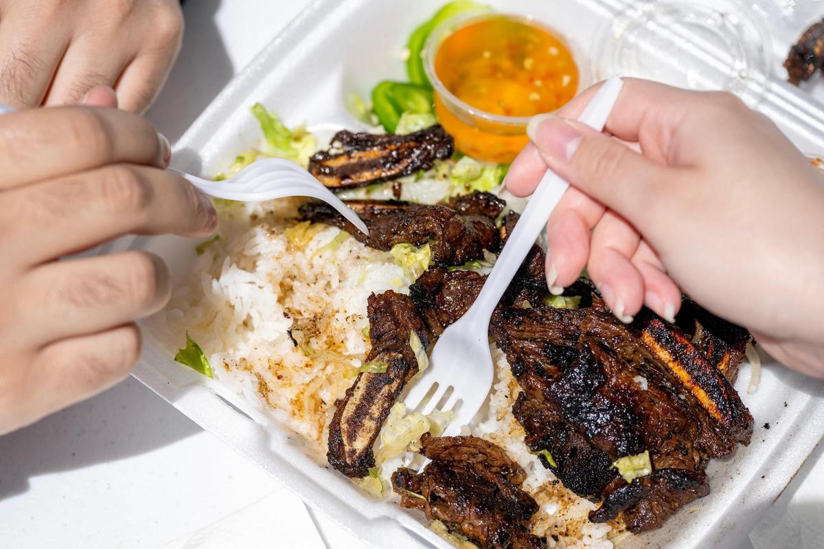 Visitors eat short ribs from the Dragon Wagon food truck Taste of AAPI festival.