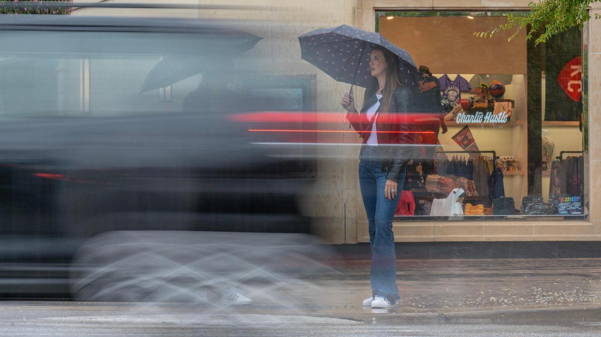 Shoppers wait to cross Broadway Boulevard at Country Club Plaza as heavy rain falls on Wednesday in Kansas City.