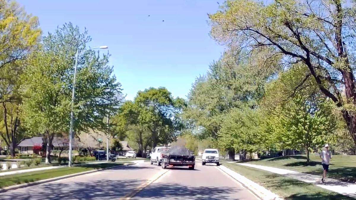 Video from a dash camera in a private vehicle captured a white Ford pickup truck driving on a sidewalk moments after allegedly striking a pedestrian in Prairie Village. The truck then turned back onto the road, forcing a truck towing a trailer to swerve to miss a collision.