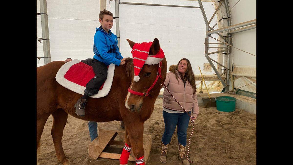 Volunteer horse handler Renee Roe spends some time with her grandson, Blaine Roe. Montey the horse is feeling festive.