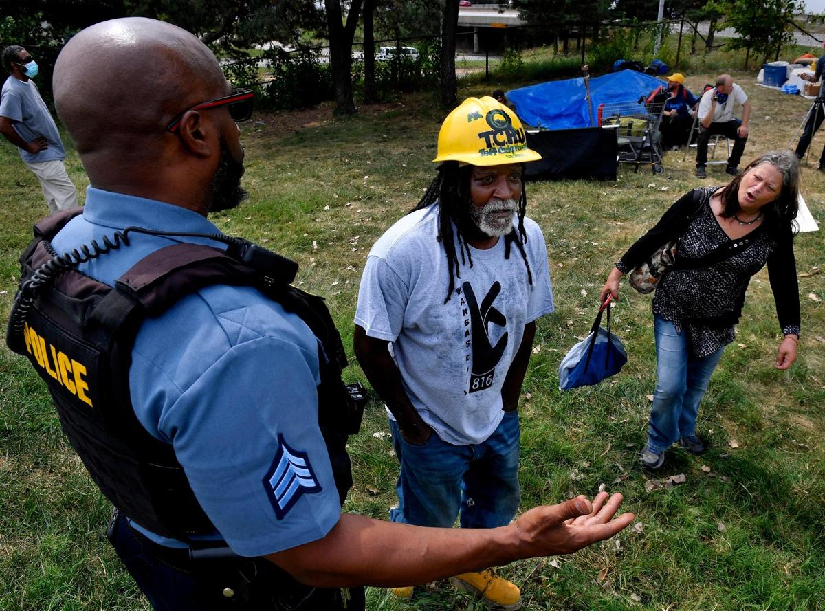 During a sweep of the camp, James Shelby, middle, the leader of the Kansas City Homeless Union, who goes by Qadafhi, and camp resident Kimberly Taylor, plead with a Kansas City police officer and Kevin Evans, a superintendent for parks and recreation, who demanded everyone vacate the park on the grounds of an ordinance that doesn’t allow camping or homesteading in city parks.&nbsp;