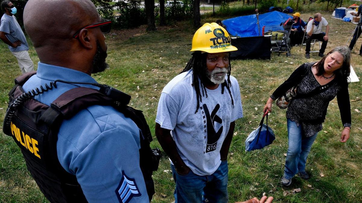During a sweep last September in a small city park near 10th Street and Harrison, James Shelby, middle, the leader of the Kansas City Homeless Union, who goes by Qadafhi, and camp resident Kimberly Taylor, plead with a Kansas City police officer and Kevin Evans, a superintendent for parks and recreation, who demanded everyone vacate the park because of an ordinance that bars camping or homesteading in city parks.