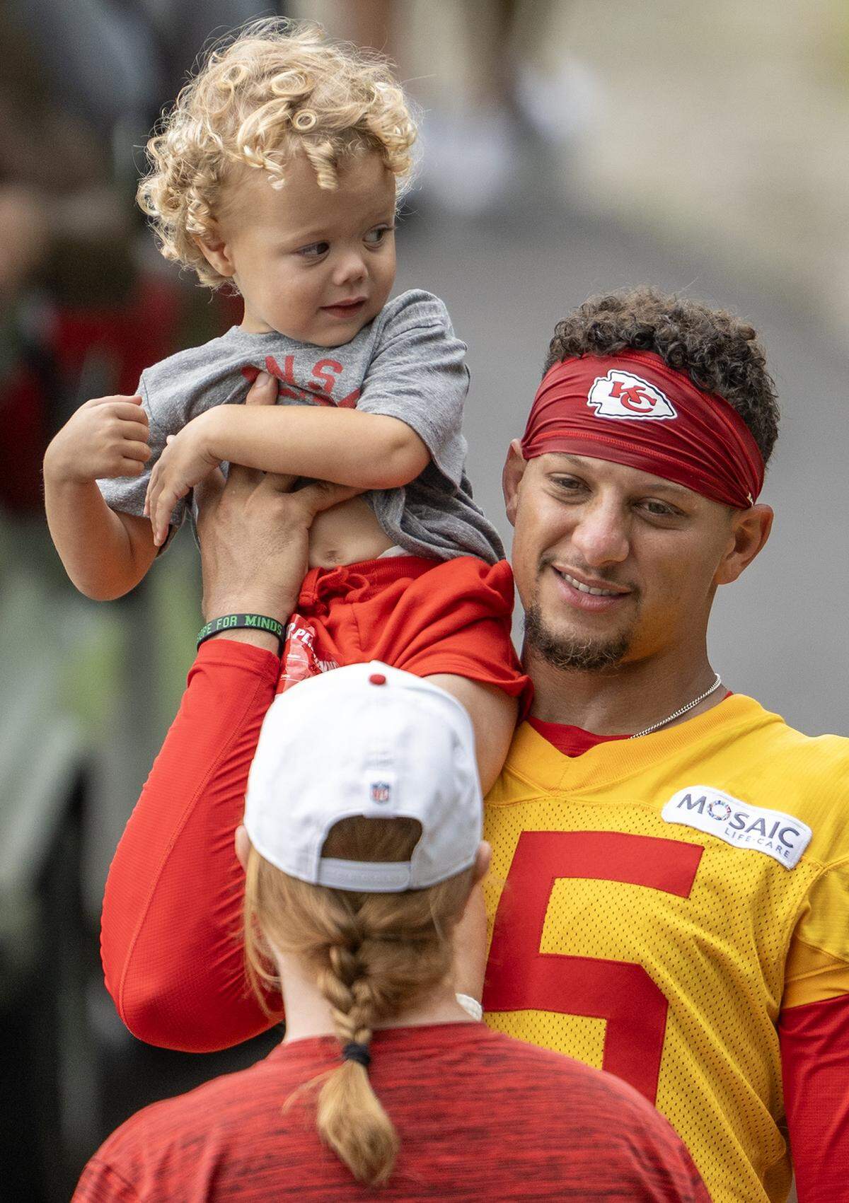 Kansas City Chiefs quarterback Patrick Mahomes (15) carries his son, Patrick "Bronze" Lavon Mahomes III at training camp at Missouri Western State University on Wednesday, July 30, 2025, in St. Joseph, Missouri.