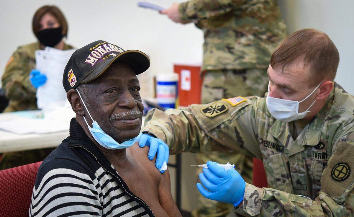 Public health officials say vaccine availability has been limited in urban counties of both Kansas and Missouri, while supplies in rural counties have been more plentiful. Leon Slaughter of Kansas City received a first dose of the Moderna vaccine from Sgt. Jeromy Eslinger of the Army National Guard at a vaccination clinic Friday at Morning Star Family Life Center in Kansas City.