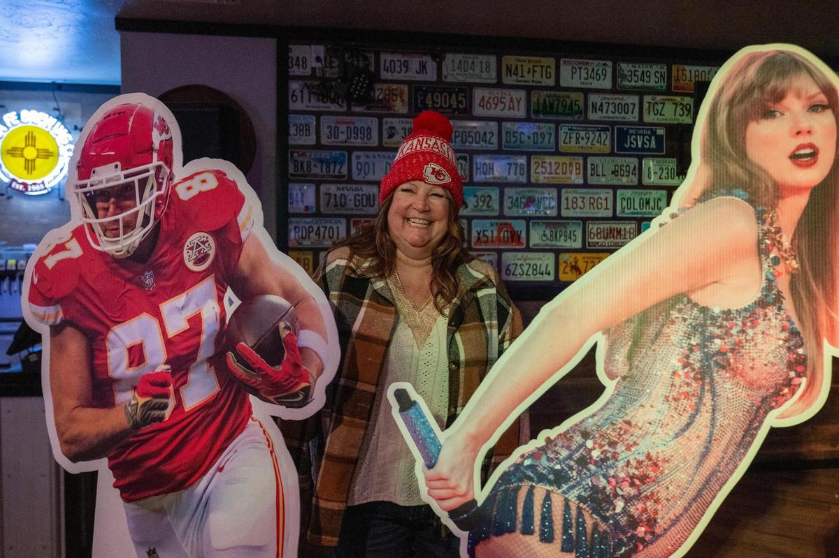 Jane Jernigan, a Kansas City Chiefs fan, takes photos with life-size cutouts of Kansas City Chiefs tight end Travis Kelce and pop star Taylor Swift at the Local Brew House.