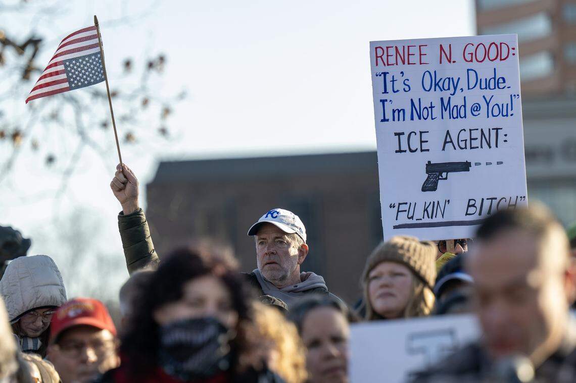 A demonstrator holds an upside-down American flag as others display a sign criticizing U.S. Immigration and Customs Enforcement during a vigil for ICE victims at Mill Creek Park on Saturday, Jan. 10, 2026, in Kansas City.
