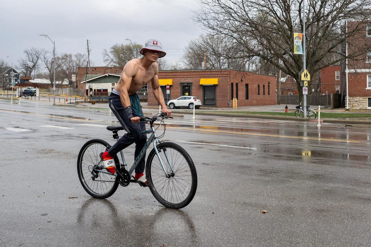 A shirtless cyclist rides down Gillham Road as rain begins to fall on Friday, March 14, in Kansas City.