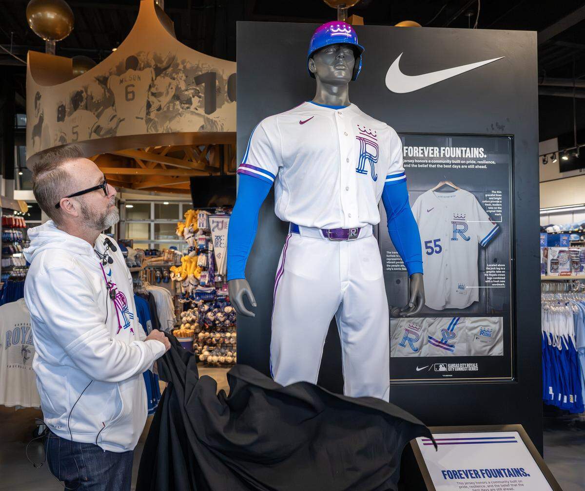Tony Snethen, chief marketing officer for the Kansas City Royals, pulls down a veil revealing the new Kansas City Royals City Connect uniforms at the Royals Team Store at Kauffman Stadium on Thursday, April 9, 2026, in Kansas City.